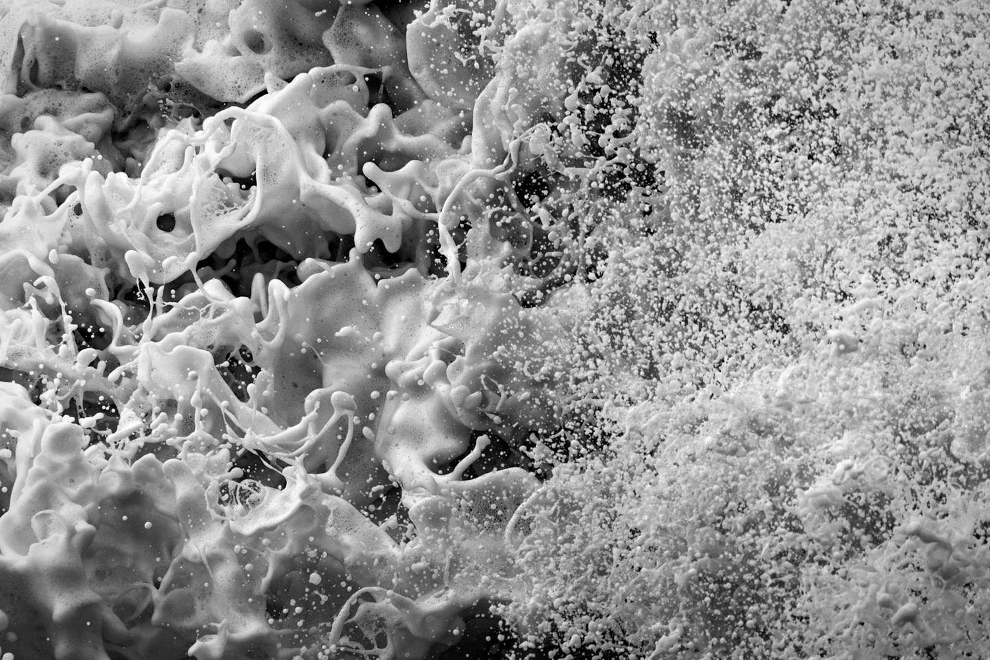 Close-up black and white photograph of textured sea foam and ocean spray, abstract coastal wall art.