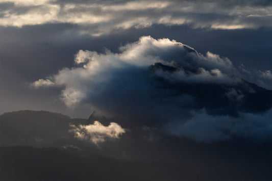 Mount Warning in New South Wales covered in a thick fog with sunrays lighting up the clouds at sunrise.